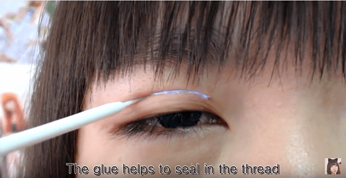 Để định hình chắc đường chỉ, bôi 1 lớp gel/keo kích mí.Sau đó dùng cây phụ kiện nâng mí lên
