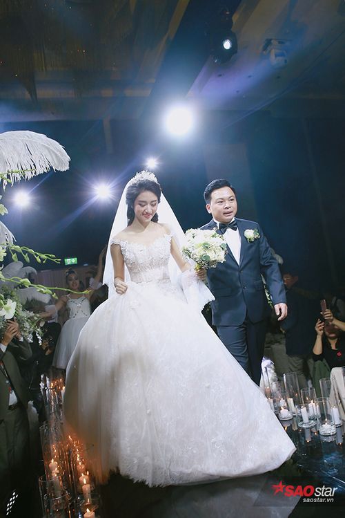 Cô dâu chú rể năm chặt tay tiến vào khán phòng làm lễ.