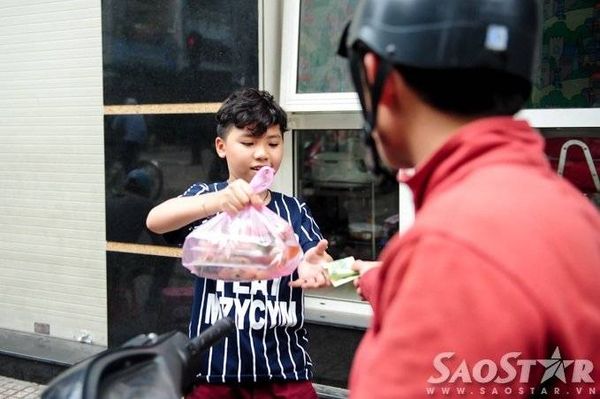 Cậu nhóc vui vẻ bán bánh cho khách trong khi mẹ mình tất bật chiết nước chấm vào túi ni lông nhằm kịp giờ giao số hàng đặt.
