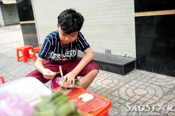 Thí sinh 12 tuổi gốc Phan Thiết giúp mẹ chất hàng ra bàn nhựa và tự tay bỏ từng chiếc chả vào các hộp bánh đang làm dang dở.
