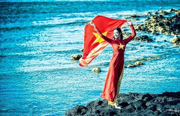 Trong trang phục áo dài truyền thống in hình cờ đỏ sao vàng, người đẹp thể hiện mạnh mẽ tình yêu nước và tình yêu biển đảo.