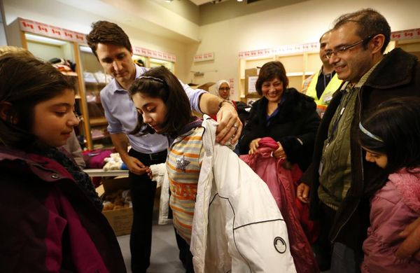 Canada's Prime Minister Justin Trudeau helps a young Syrian refugee try on a winter coat after she arrived with her family from Beirut at the Toronto Pearson International Airport in Mississauga, Ontario, December 11, 2015. REUTERS/Mark Blinch