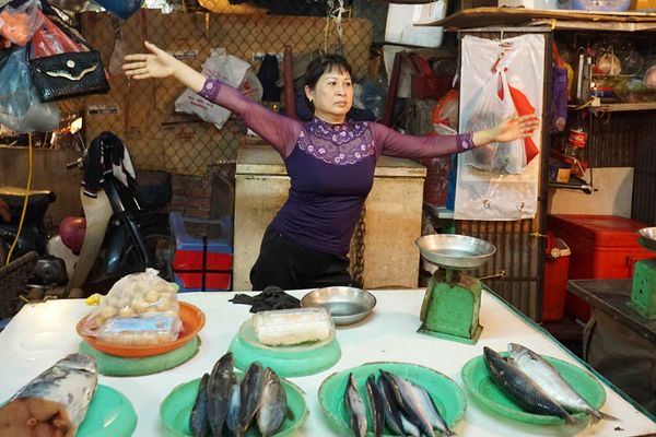 Để việc bán hàng không bị ảnh hưởng, các chị chỉ tập trong giờ vắng khách. Khi có người mua hàng, họ lại tạm dừng để bán như bình thường. Trong ảnh là chị Kiều Hạnh, 50 tuổi, chuyên bán cá đông lạnh, đang luyện Aerobic. Chị chia sẻ, cũng có thể đến lớp học Aerobic được nhưng thấy rất mất thời gian và ảnh hưởng đến buôn bán nên tranh thủ tập ngay tại sạp bán hàng. Tiện đủ đường !