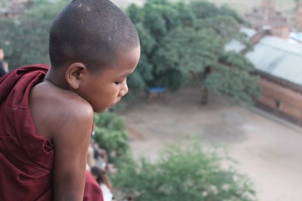 ... và một chú tiểu ngồi cùng vài du khách trên những bậc thang của chùa Shwe San Daw trong ánh mặt trời.
